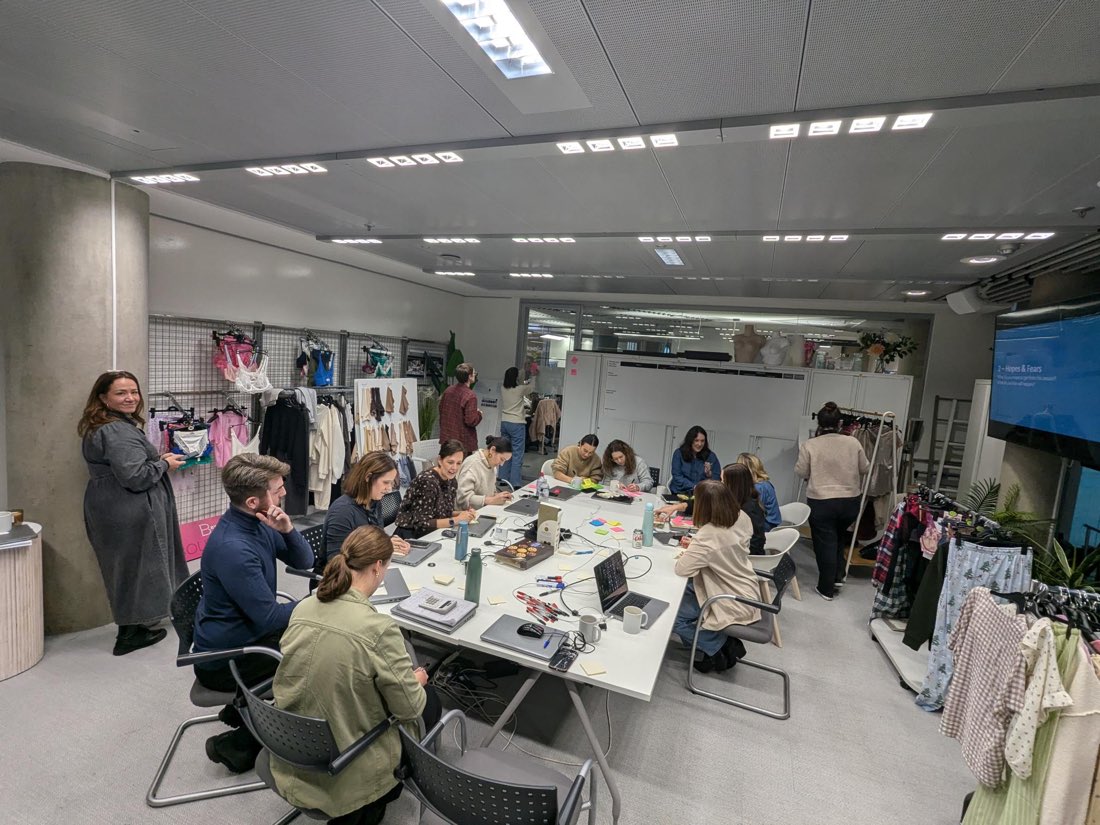 A team mid-workshop, the table covered in laptops and sticky notes
